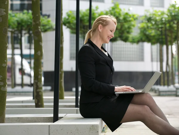 Affärskvinna leende med laptop utanför — Stockfoto