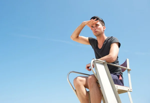 Portrait of a lifeguard sitting in chair on summer day — Stock Photo, Image