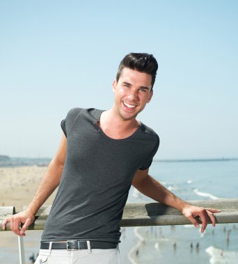 Deniz kenarında gülümseyen çekici bir genç adam portresi