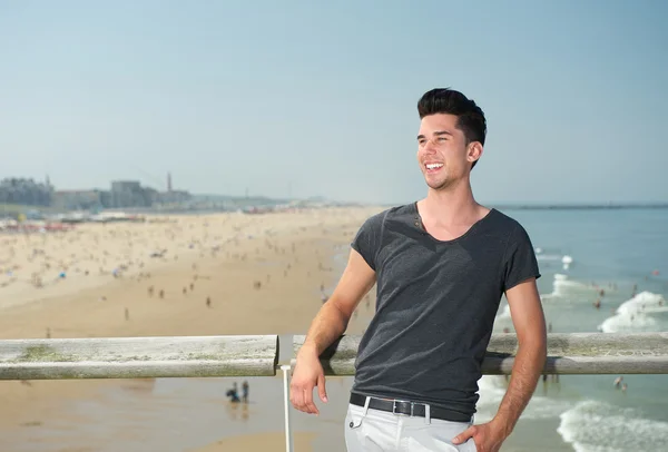 Glücklicher junger Mann lächelt im Urlaub am Strand — Stockfoto