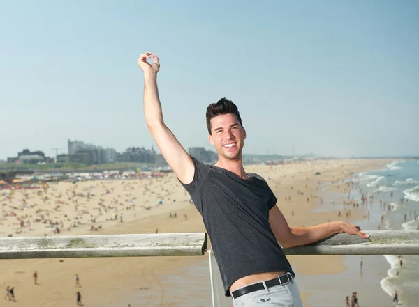 Heureux jeune homme avec le bras levé au bord de la mer — Photo