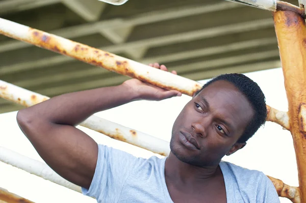 Guapo modelo masculino sentado al aire libre y sosteniendo escaleras barandilla — Foto de Stock