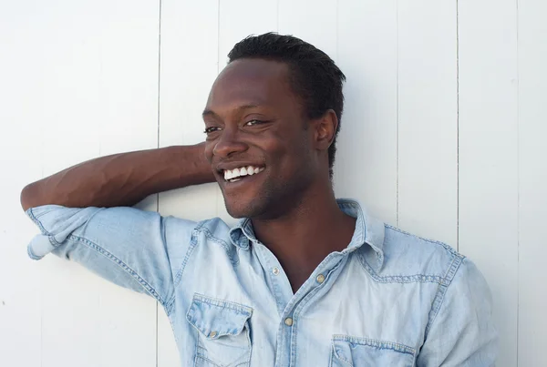 Gelukkig jonge african american man die lacht tegen witte achtergrond — Stockfoto