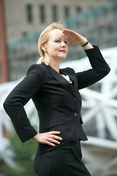 Affärskvinna med handen till huvudet salute i staden — Stockfoto
