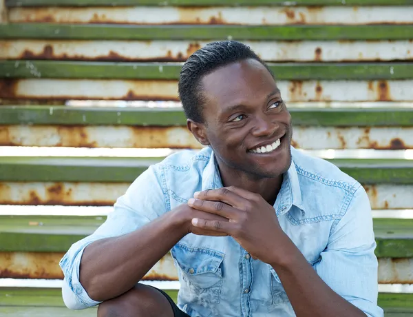 Souriant homme afro-américain assis à l'extérieur — Photo