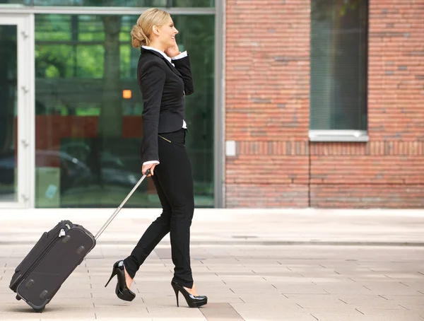 stock image Business woman walking with luggage and talking on phone