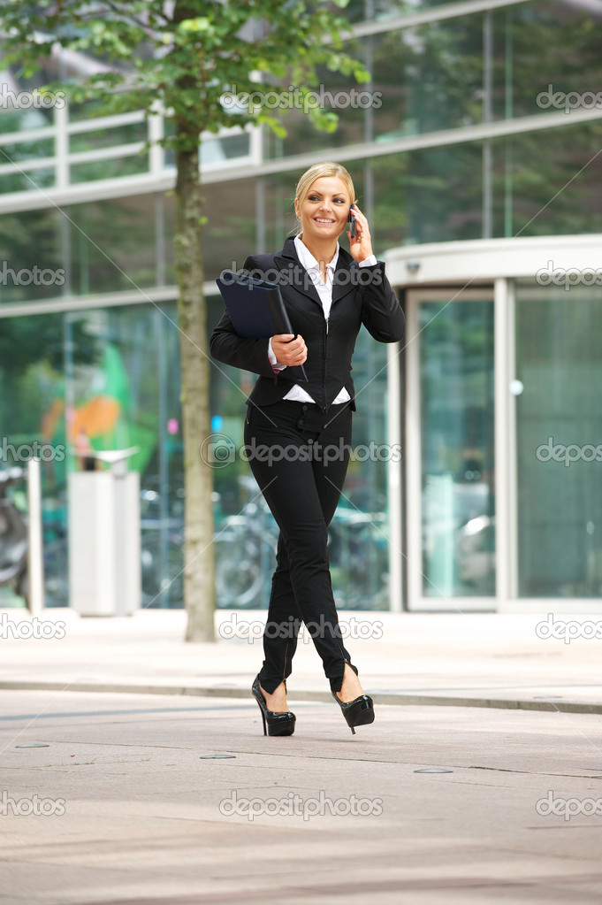 Business woman walking outdoors and talking on mobile phone