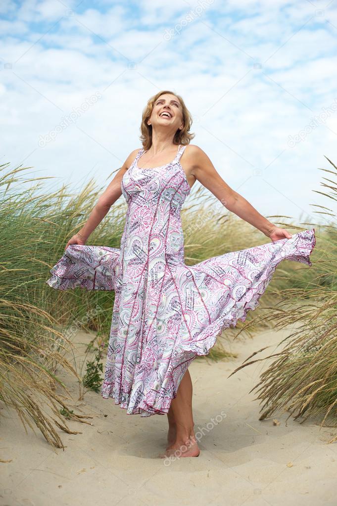 Carefree older woman dancing at the beach