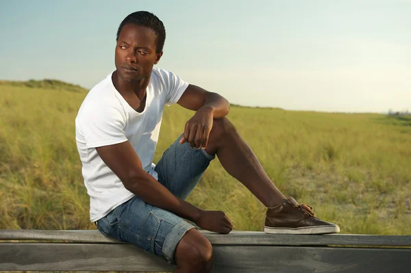 Portrait of a handsome young man sitting alone outside — Stock Photo, Image