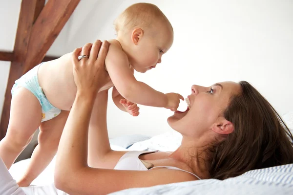 Portrait of a happy mother and baby playing in bed — Stock Photo, Image