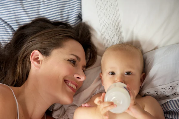 Retrato de uma mãe feliz com bebê bonito bebendo de garrafa — Fotografia de Stock