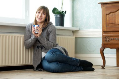 Happy young woman relaxing at home with a cup of tea