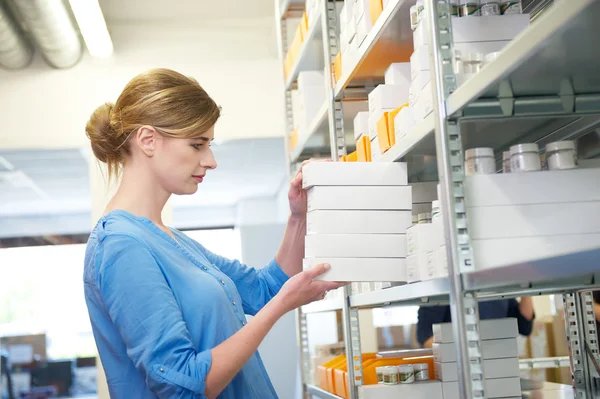 Young female worker holding boxes in warehouse — Stock Photo, Image