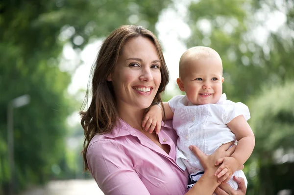 Portret van een mooie moeder met lachende baby buitenshuis — Stockfoto