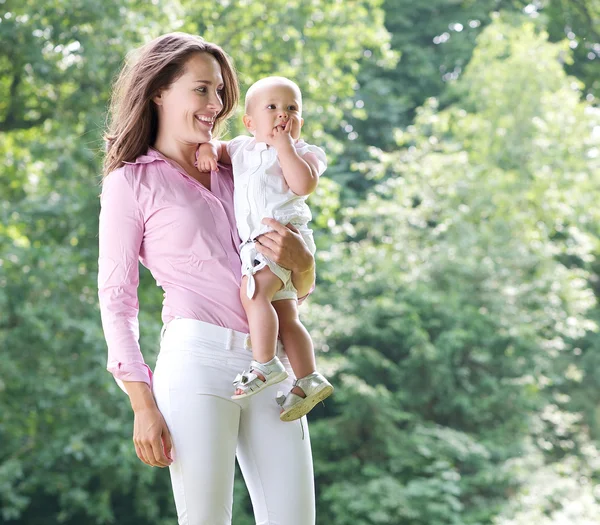 Porträtt av en vacker mor anläggning baby i parken — Stockfoto