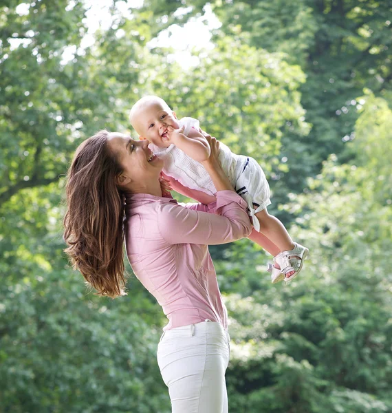 Portret van een gelukkige moeder spelen met baby in het park — Stockfoto
