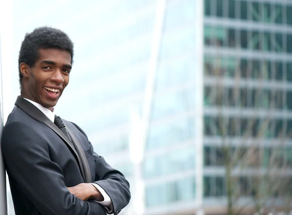 Vrolijke jonge zakenman glimlachend in de stad — Stockfoto