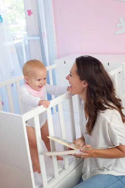 Happy mother smiling at baby in crib — Stock Photo, Image