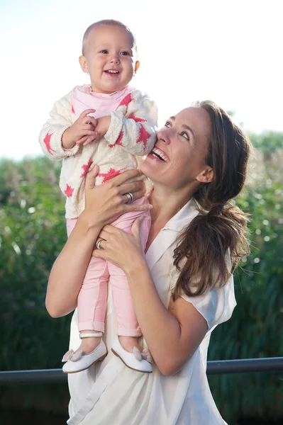 Junge Mutter lächelt draußen mit entzückendem Baby — Stockfoto