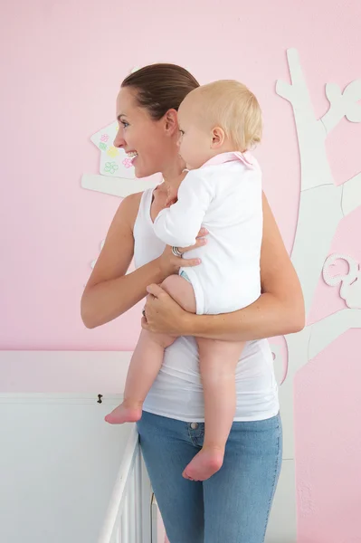 Mujer joven sosteniendo lindo bebé y mirando hacia otro lado —  Fotos de Stock