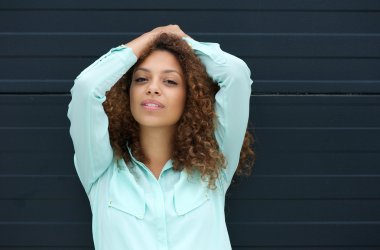 elleri saçlarında gülümseyen genç ve güzel bir kadın portresi