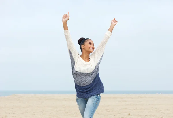 Zorgeloos jonge vrouw met uitgestrekte armen wandelen op het strand — Stockfoto