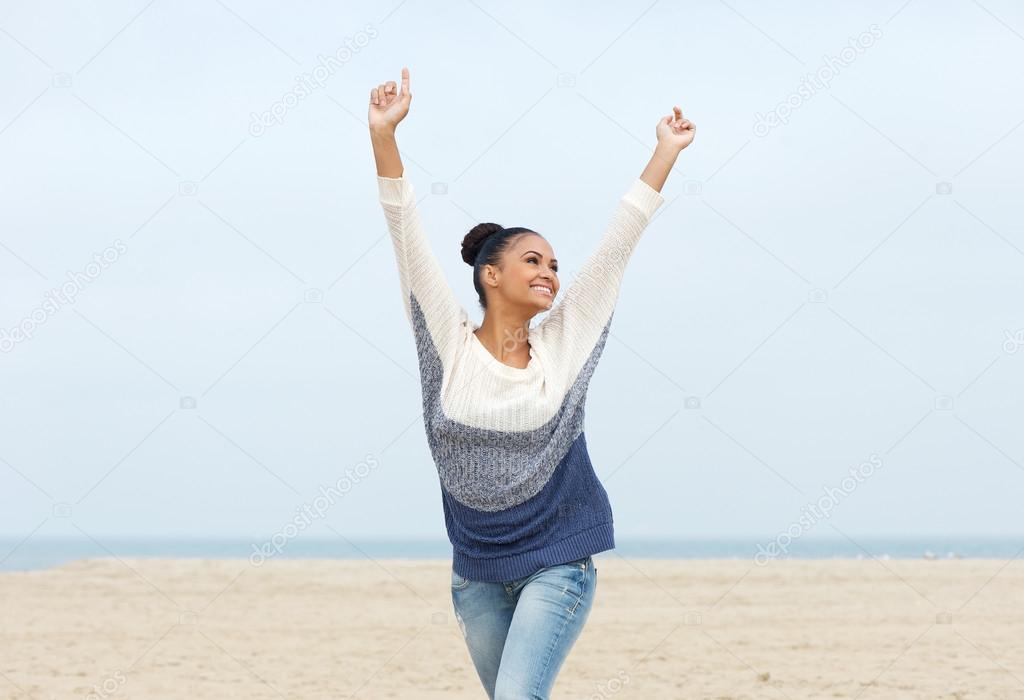 Carefree young woman with arms outstretched walking on the beach