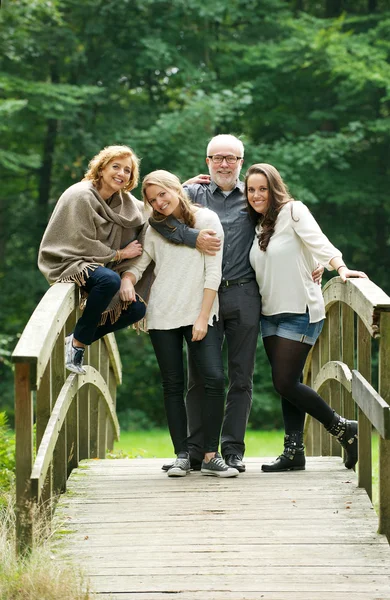 Glad familj står tillsammans på en bro i skogen — Stockfoto