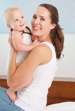 Holding ve sevimli gülümseyen bebekle oynarken mutlu anne