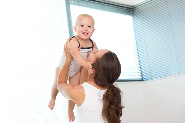 Glückliche Mutter hebt süßes Baby zu Hause hoch — Stockfoto