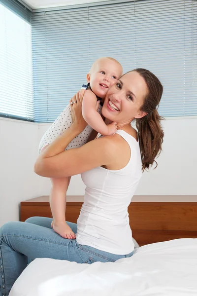 Atractiva joven madre sosteniendo lindo bebé en el dormitorio —  Fotos de Stock
