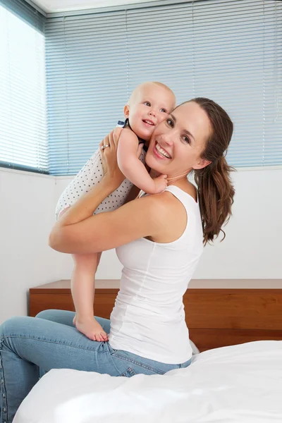 Aantrekkelijke jonge moeder bedrijf schattige baby in slaapkamer — Stockfoto