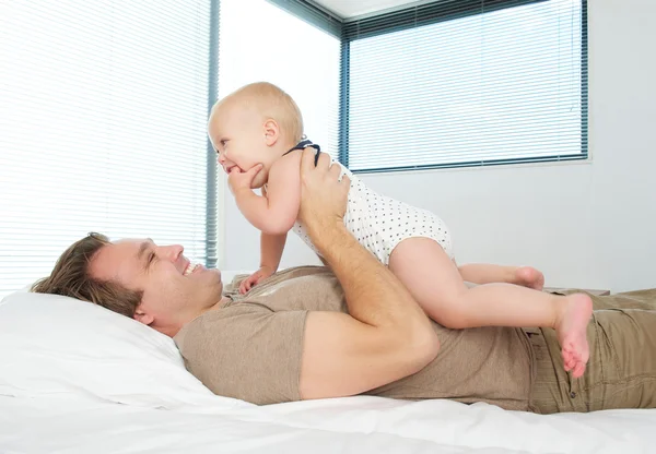 Счастливый отец держит ребенка в постели — стоковое фото