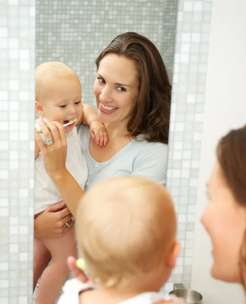Beautiful smiling woman teaching baby how to brush teeth — Stock Photo, Image