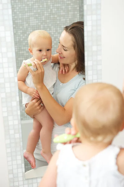 Mãe feliz ensinando bonito bebê enxada para escovar os dentes — Fotografia de Stock