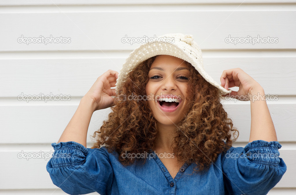 Cheerful young woman with hate laughing outdoors