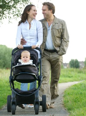 mutlu anne ve baba gülümseyerek ve çocuk ile bebek arabası itme