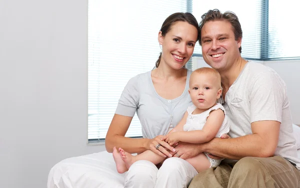 Glad mamma och pappa sitter hemma med söt baby — Stockfoto