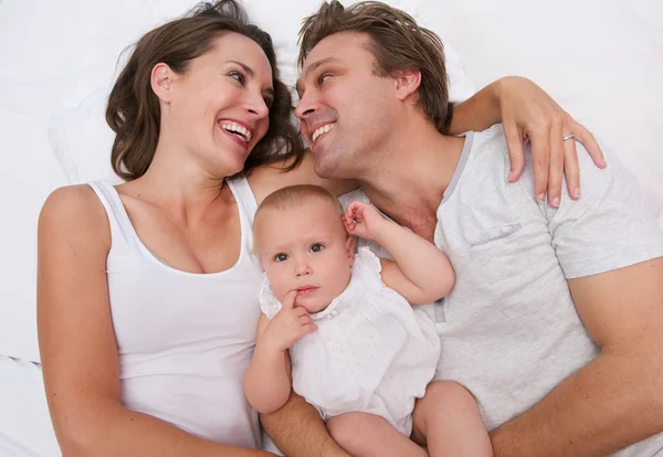 Retrato de uma família amorosa segurando bebê bonito na cama — Fotografia de Stock