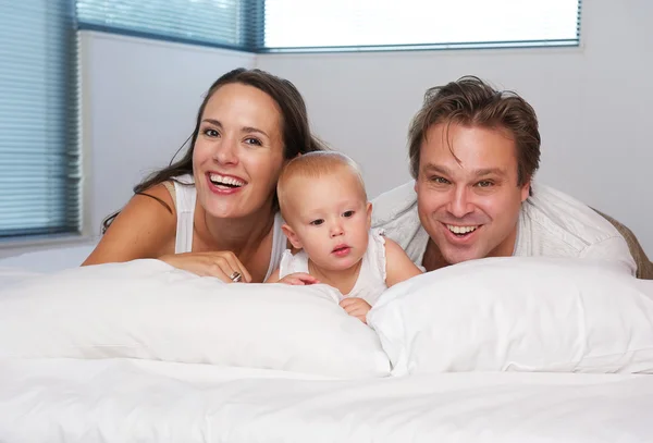 Feliz familia cariñosa acostado en la cama con el bebé lindo —  Fotos de Stock