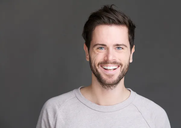 Portrait of a happy young man smiling on gray background