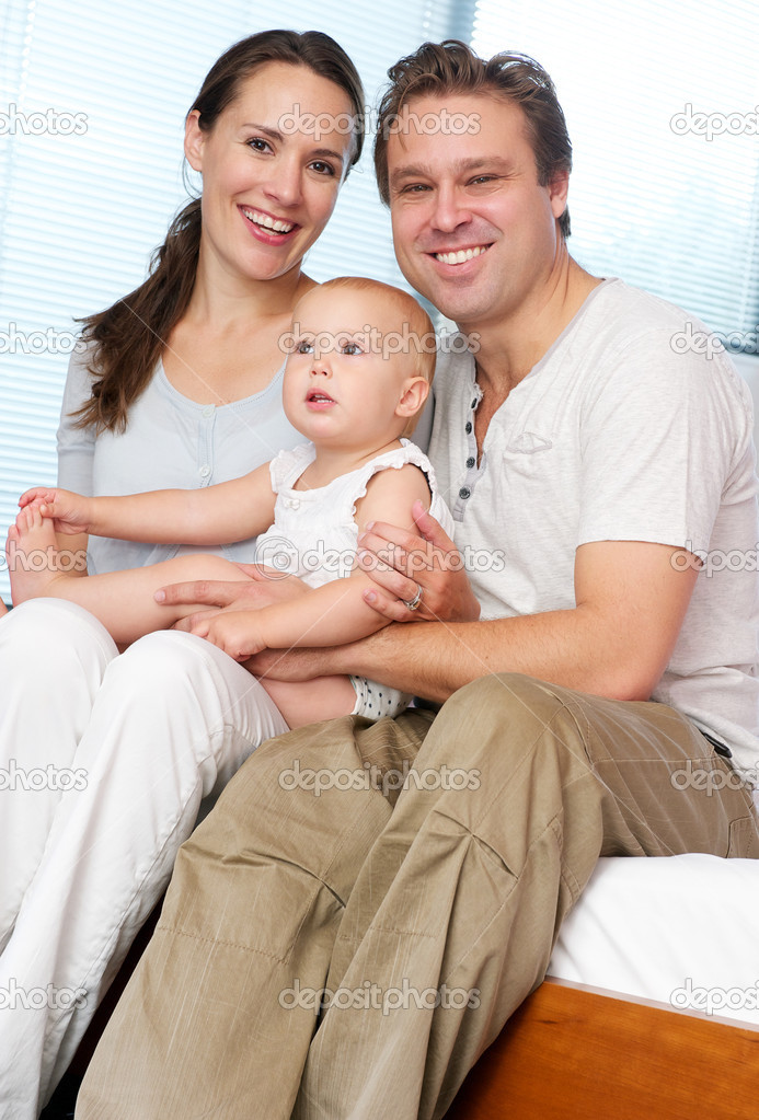 Happy Loving Couple Holding Cute Baby At Home Stock Photo