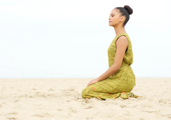 Mladá žena sedí sám a meditovat na pláži — Stock fotografie