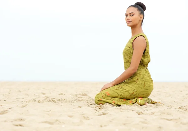 Schöne junge Frau sitzt allein auf Sand am Strand — Stockfoto