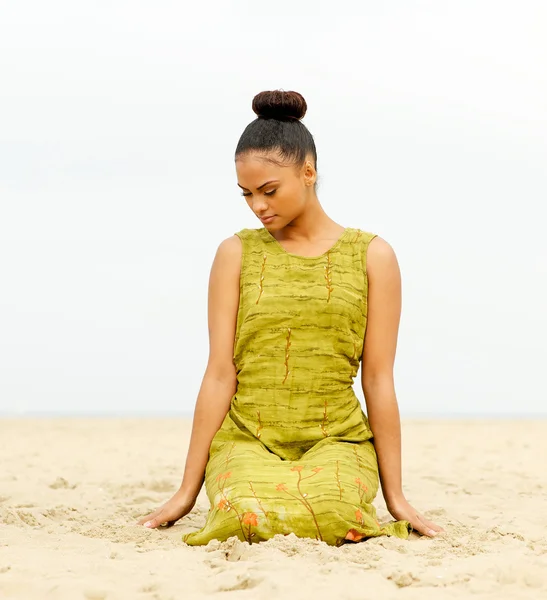 Attraktiv kvinna sitter på stranden och mediterar — Stockfoto