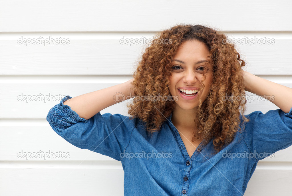 Portrait of a happy young woman smiling with hands in hair