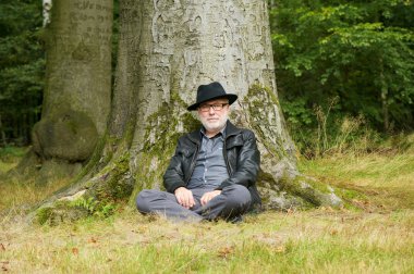 ağacın altında oturup çekici yaşlı adam