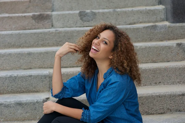 Fröhliche junge Frau lächelt draußen mit der Hand im Haar — Stockfoto