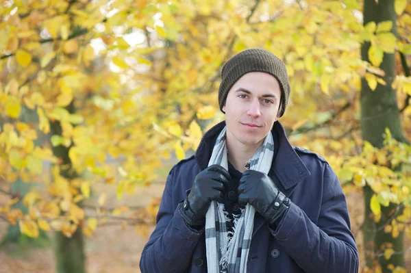 Handsome young man standing outdoors with jacket hat scarf and gloves — Stock Photo, Image