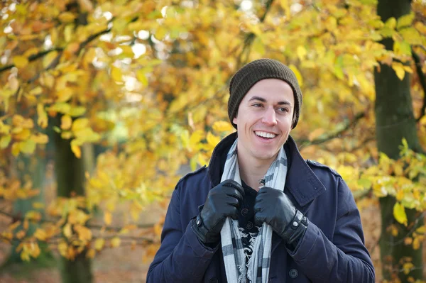 Portrait of a young man smiling outdoors in jacket gloves hat scarf — Stock Photo, Image
